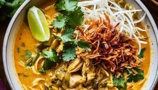A bowl of Chicken Curry Noodle Soup topped with herbs and spices