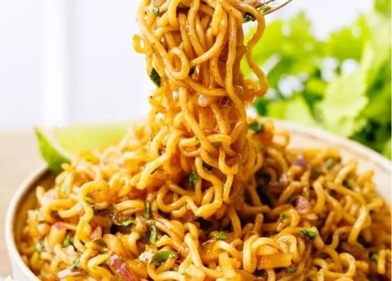 Plate of cilantro lime noodles garnished with fresh cilantro and lime slices.