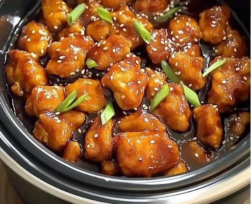 Crockpot Orange Chicken in a bowl served with rice and garnished with green onions