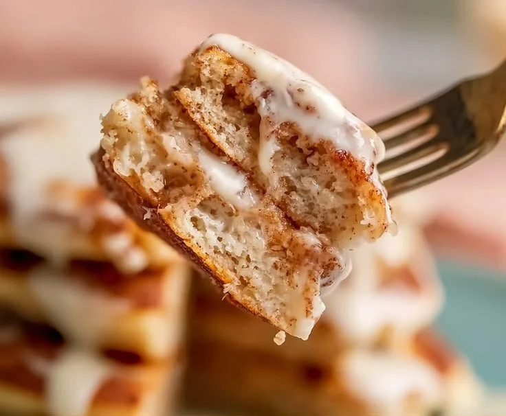 Fluffy cinnamon roll pancakes topped with icing and cinnamon swirl.