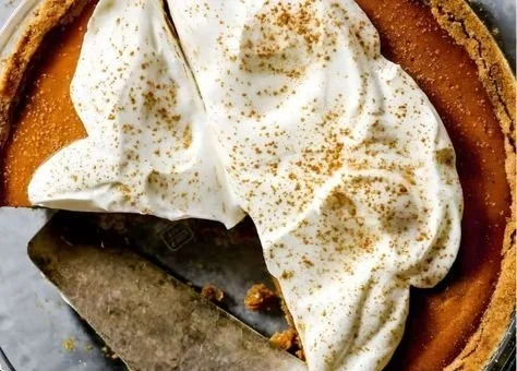 Delicious pumpkin pie with a graham cracker crust topped with whipped cream