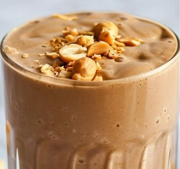 Creamy peanut butter protein smoothie in a glass with a straw.