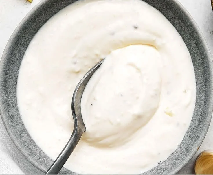 Homemade easy garlic aioli sauce in a small bowl with garlic cloves