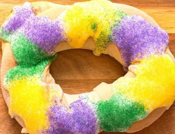 Easy homemade King Cake decorated with colorful icing and sprinkles.