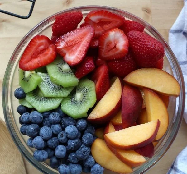 Colorful fruit salad with honey lime dressing in a bowl.