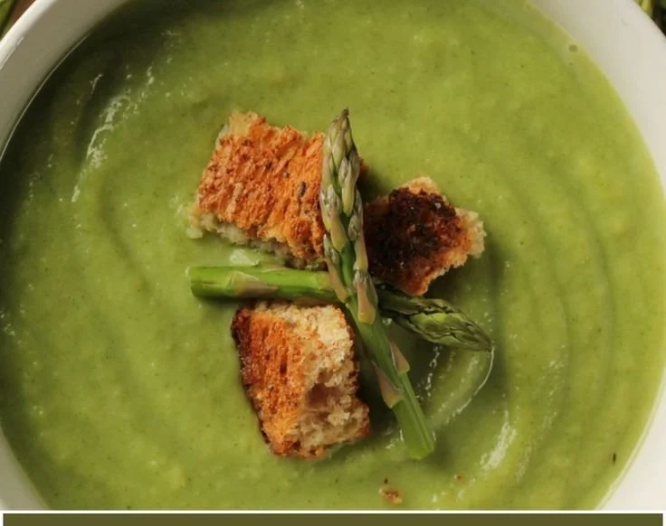 Delicious bowl of Gordon Ramsay's creamy asparagus soup garnished with herbs.