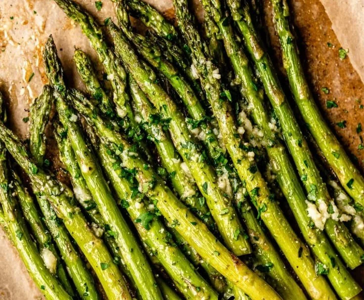 Grilled asparagus drizzled with garlic butter, served as a delicious side dish.