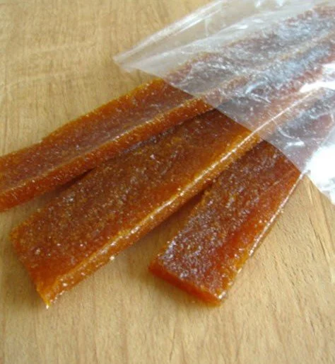 Homemade apricot fruit leather slices on a wooden table.