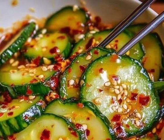 A vibrant bowl of Korean Cucumber Salad garnished with sesame seeds and herbs