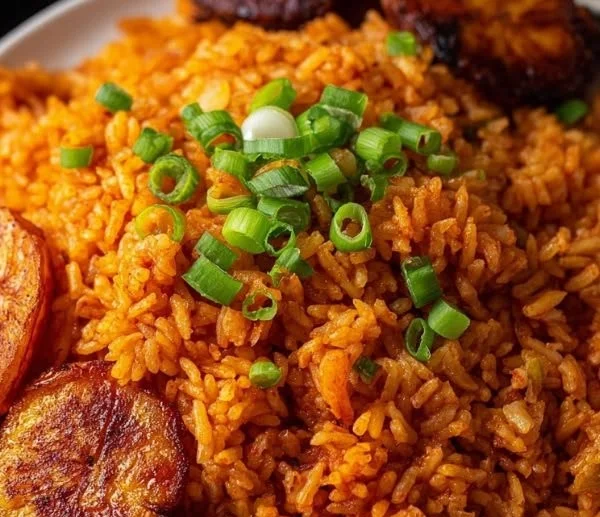 Bowl of vibrant Nigerian Jollof Rice garnished with herbs and spices
