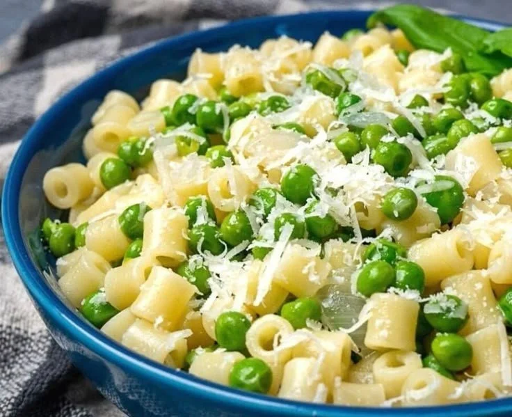 Delicious pasta and peas dish garnished with fresh herbs and parmesan cheese.