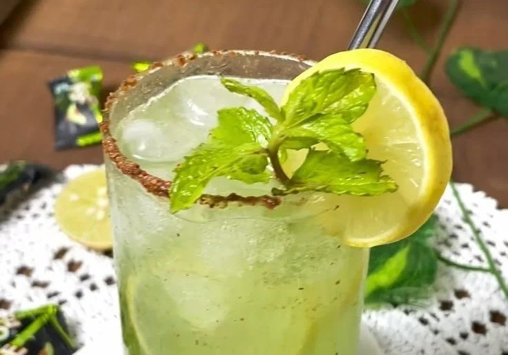 Glass of refreshing Raw Mango Mocktail garnished with mint leaves.