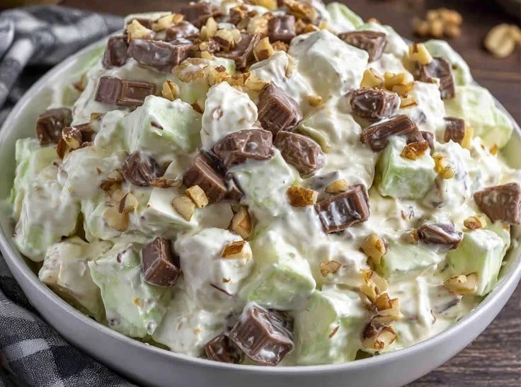 Delicious Snickers Salad served in a bowl, featuring apples, whipped cream, and Snickers bars.