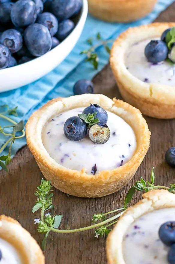 Blueberry cheesecake cookie cups topped with fresh blueberries and cream cheese