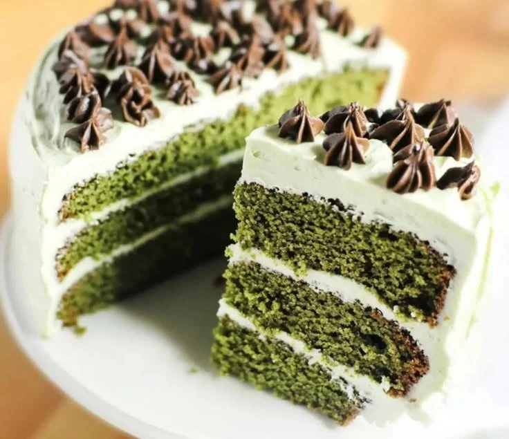Slice of vibrant Green Velvet Cake with cream cheese frosting
