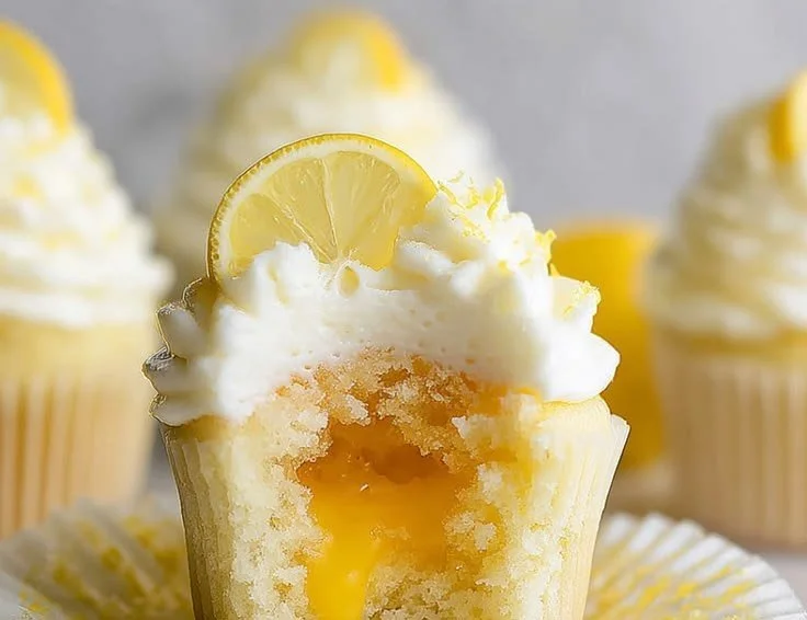 Lemon stuffed cupcakes topped with zesty frosting and fresh lemon slices.