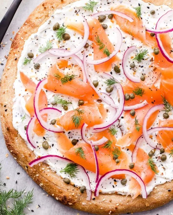 Delicious smoked salmon pizza topped with fresh herbs and cream cheese