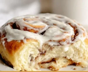 Giant homemade cinnamon rolls with icing on a wooden table