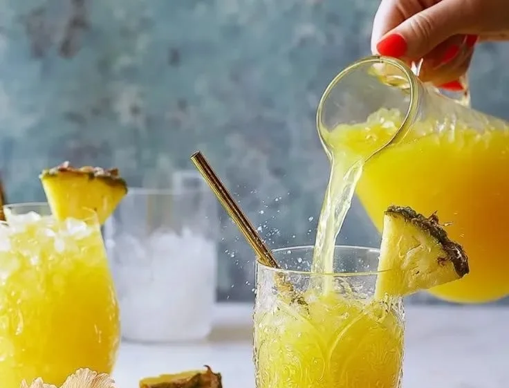 Fresh pineapple water in a glass with slices of pineapple beside it