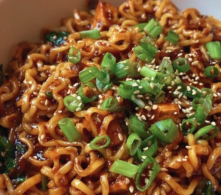 Bowl of easy saucy ramen noodles topped with vegetables and herbs