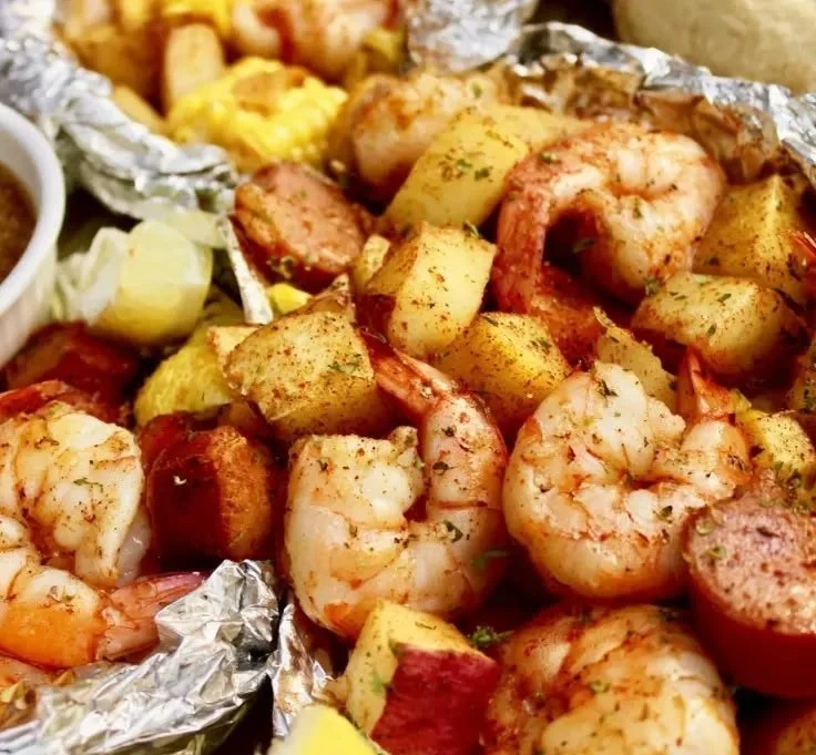Shrimp boil foil packets cooked on the grill with corn and potatoes.