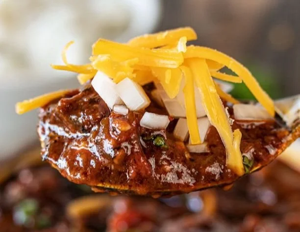 Bowl of Gochujang Chile Con Carne with fresh chiles and beef, garnished with cilantro.