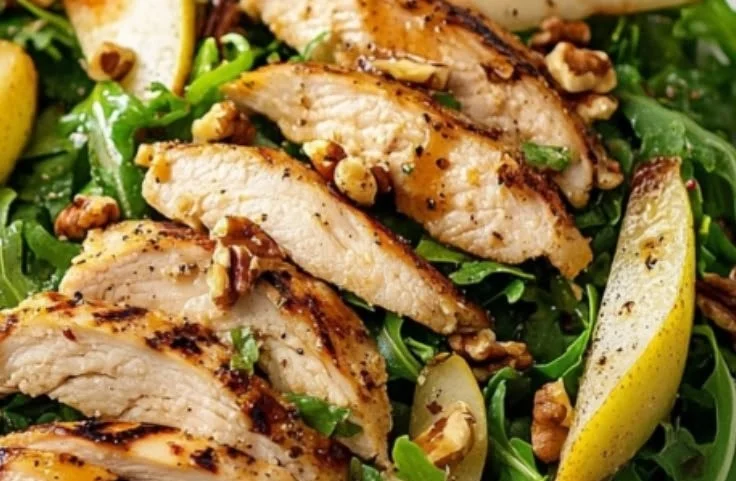 Grilled chicken salad with arugula, pears, and walnuts on a plate