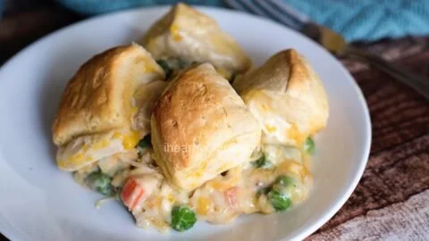 Homemade chicken pot pie with flaky biscuits, served in a rustic dish.