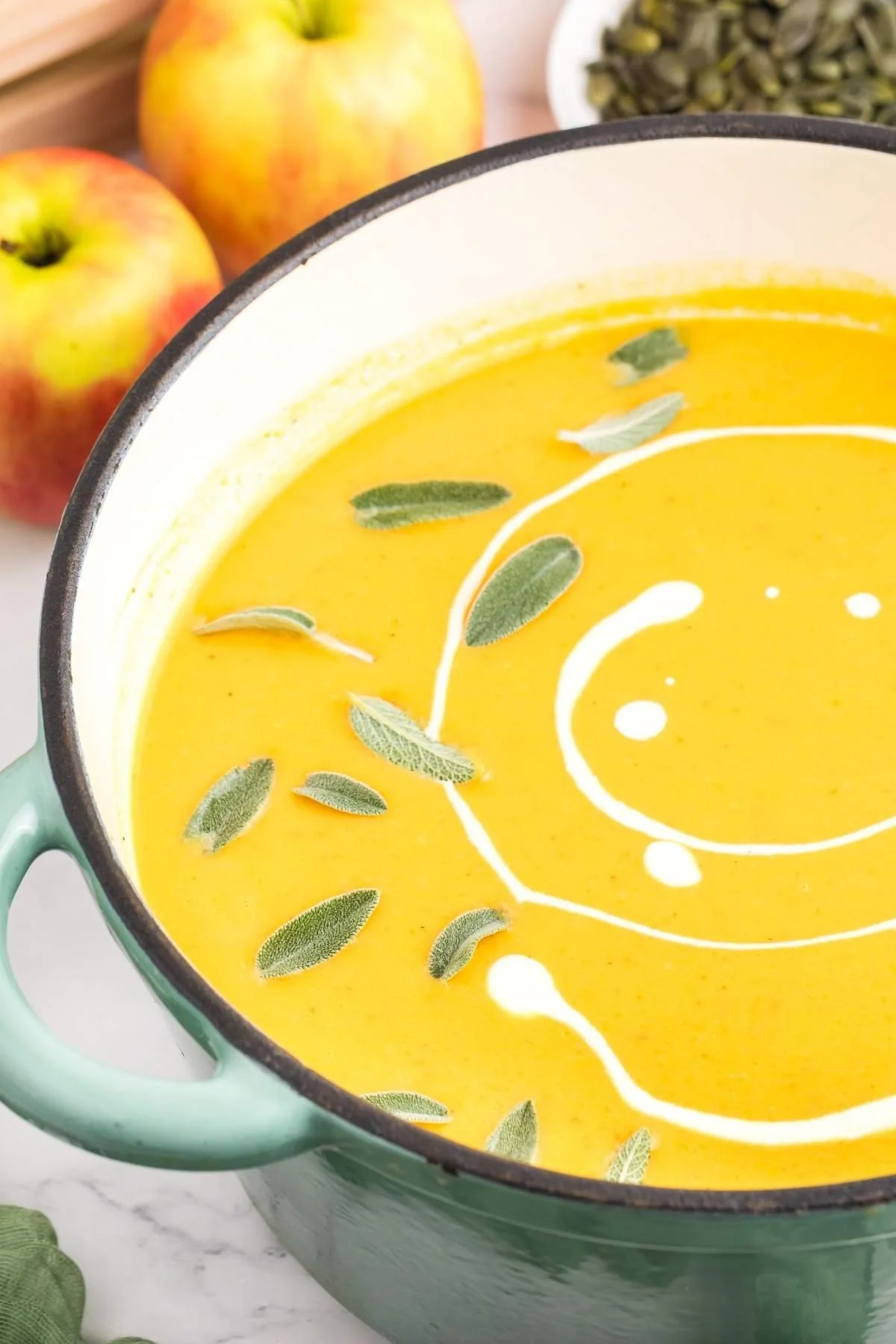 Creamy roasted apple pumpkin soup in a bowl garnished with fresh herbs
