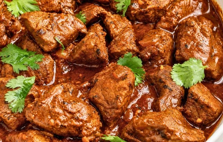 A delicious plate of Easy Beef Vindaloo served with rice and garnished with cilantro.
