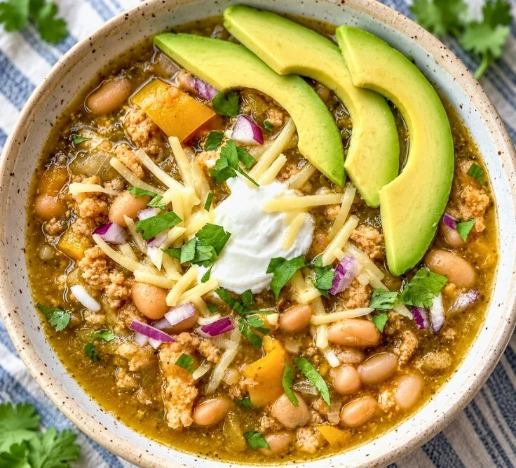 Bowl of easy white bean turkey chili verde topped with fresh cilantro and avocado.